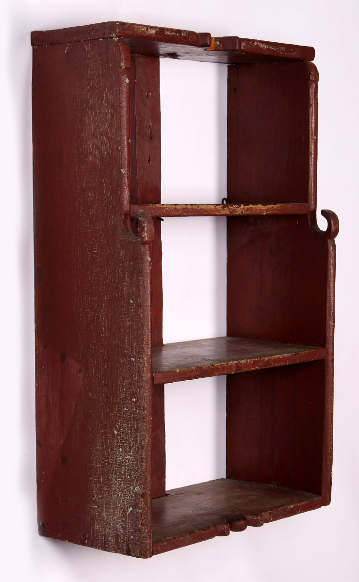 A 19TH CENTURY WALL HANGING SHELF IN OLD RED PAINT