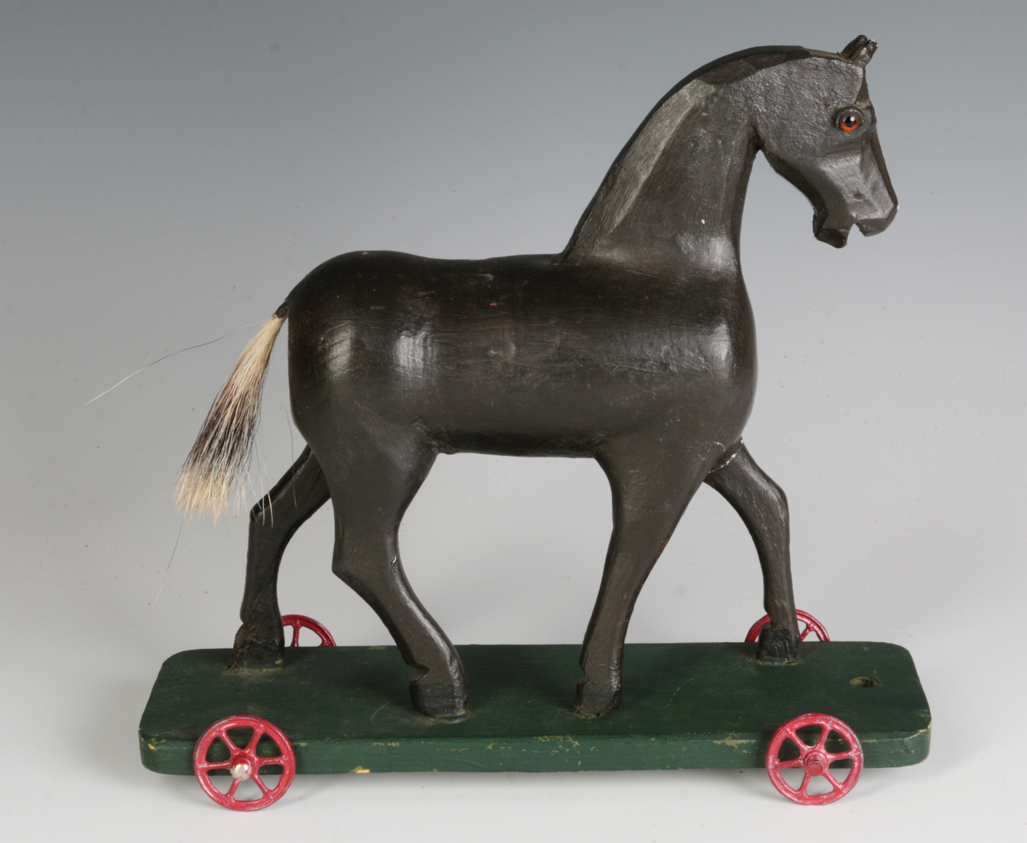 A CIRCA 1900 FOLK ART CARVED WOOD PLATFORM HORSE