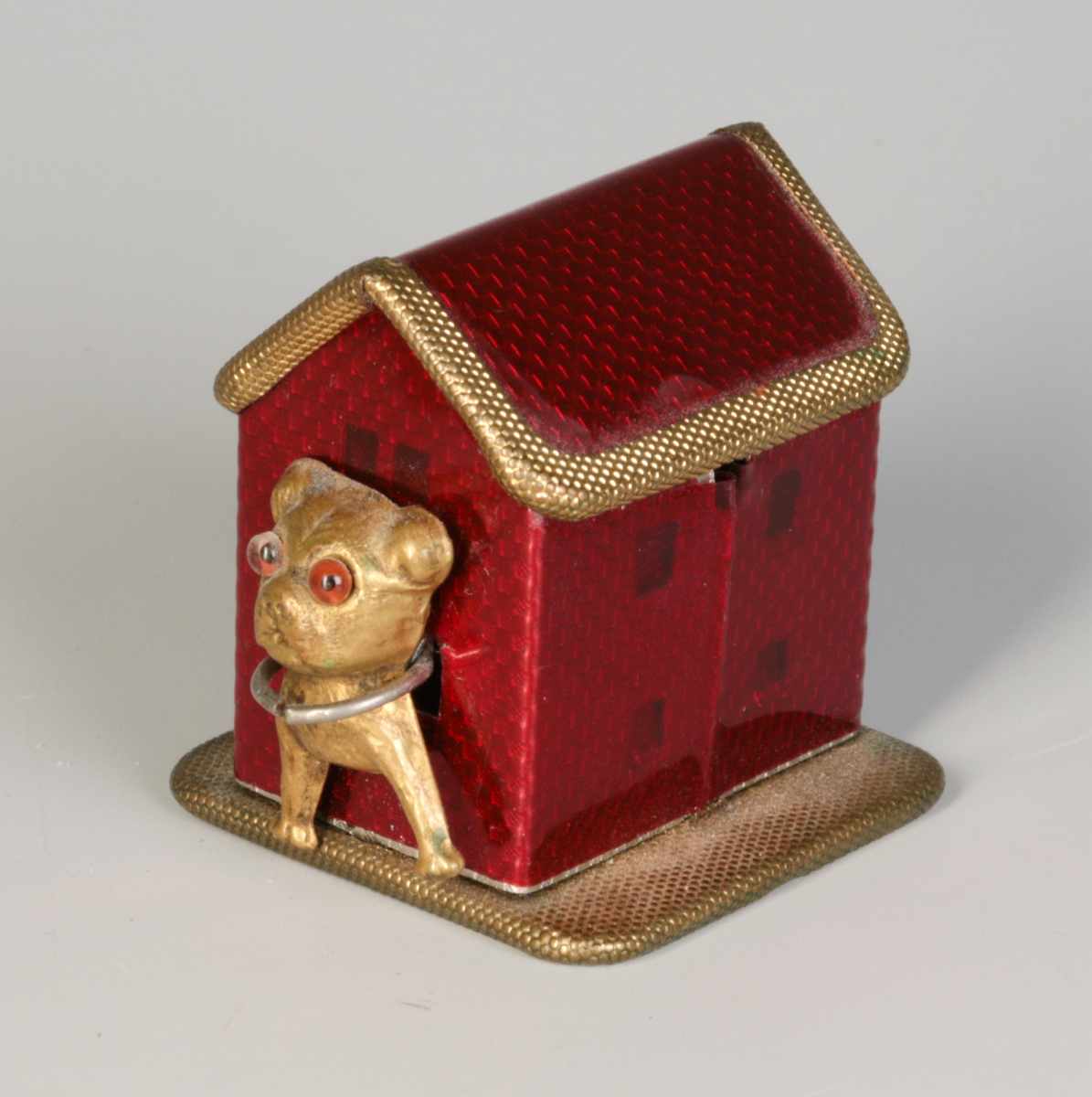 AN ENAMELED BRASS DOG IN DOG HOUSE TAPE MEASURE