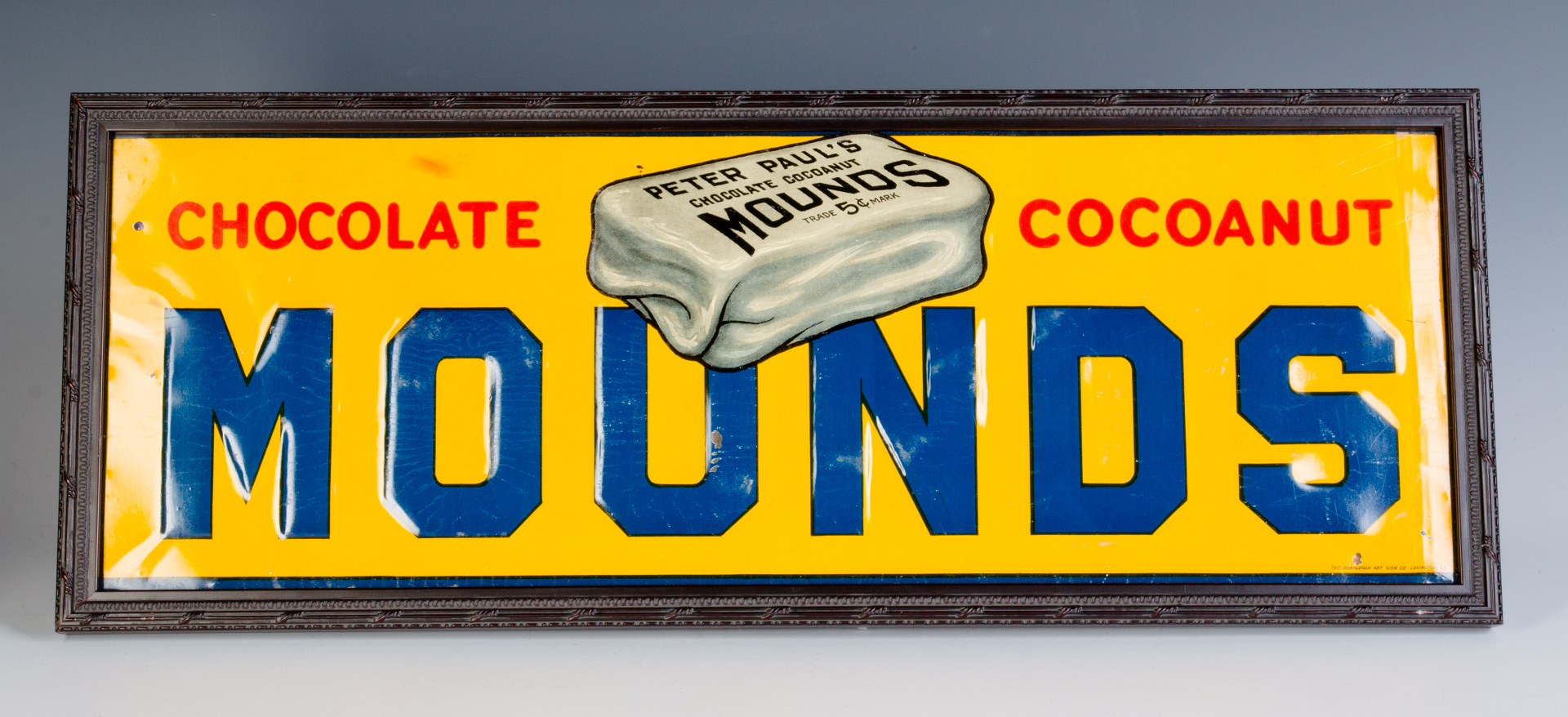 AN EMBOSSED TIN SIGN ADVERTISING MOUNDS CANDY BAR