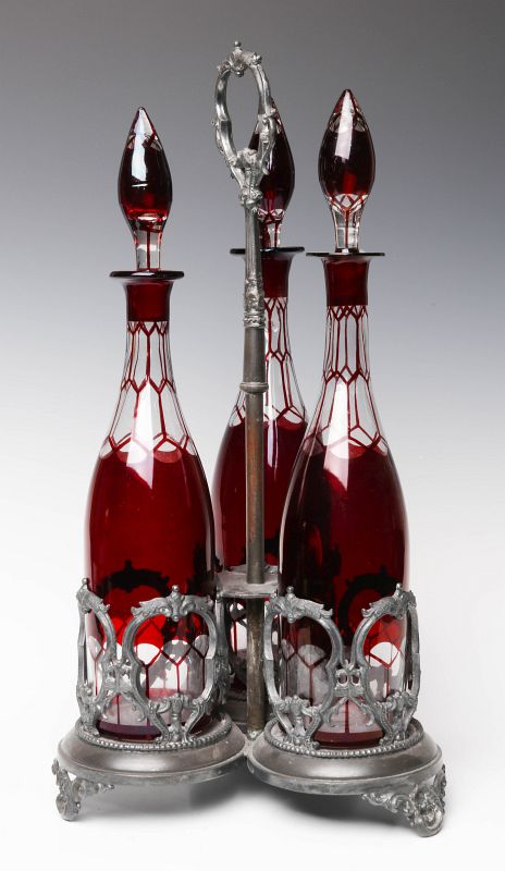 THREE RUBY FLASH WINE DECANTERS IN STAND