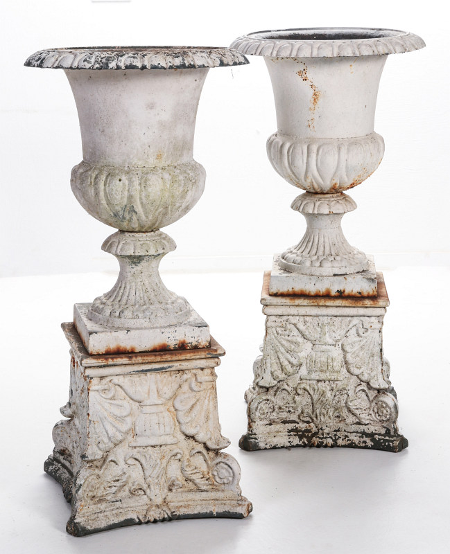A PAIR OF CAMPAGNA FORM CAST IRON URNS ON PLINTHS
