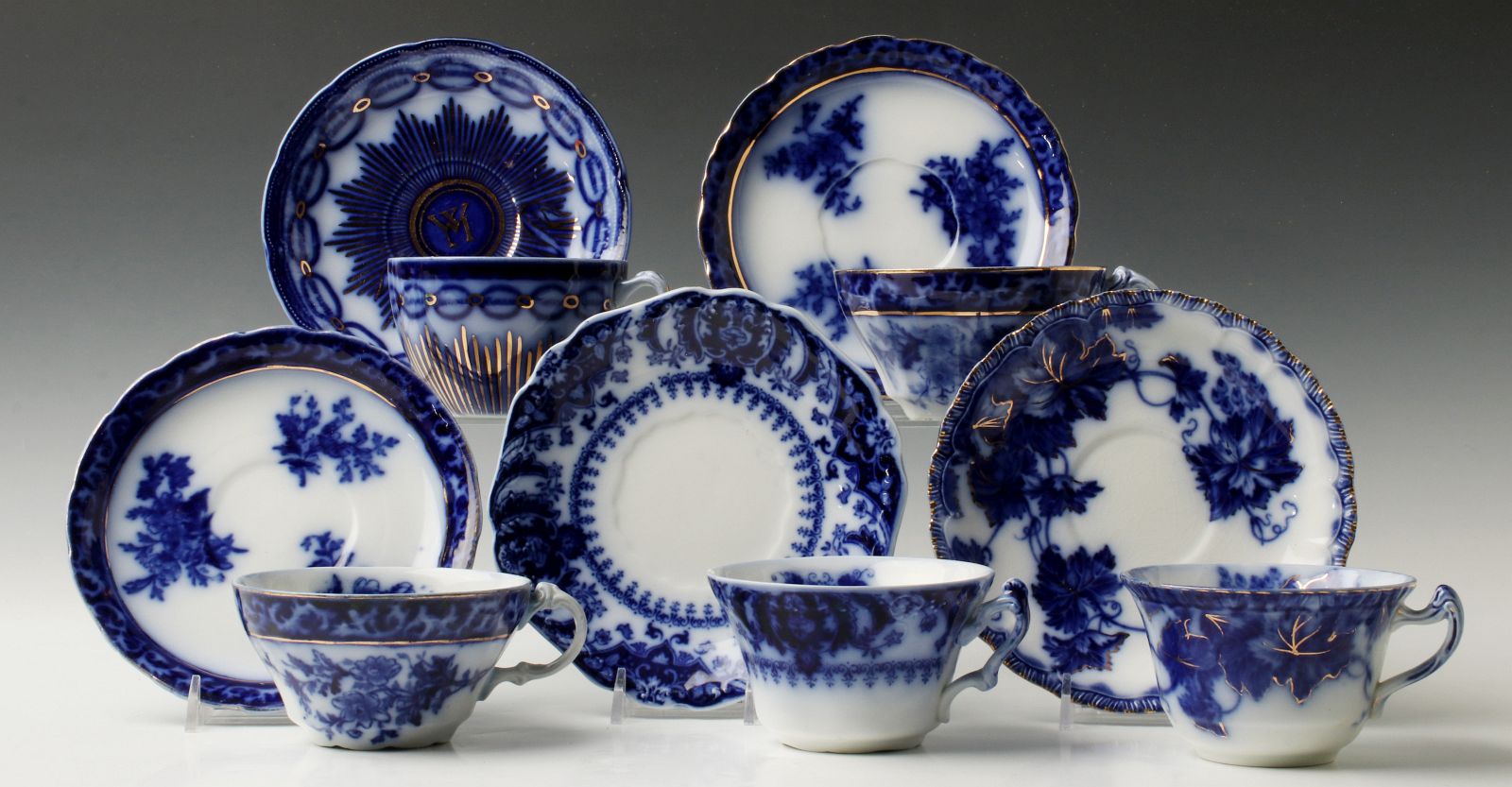 A COLLECTION OF UNUSUAL FLOW BLUE CUPS AND SAUCERS
