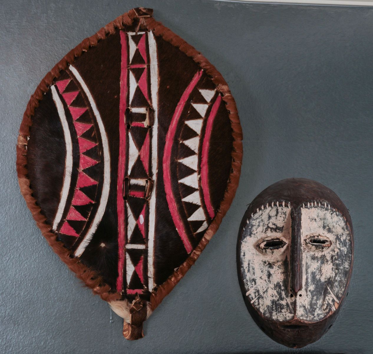 A CARVED AFRICAN MASK AND HIDE WARRIOR SHIELD