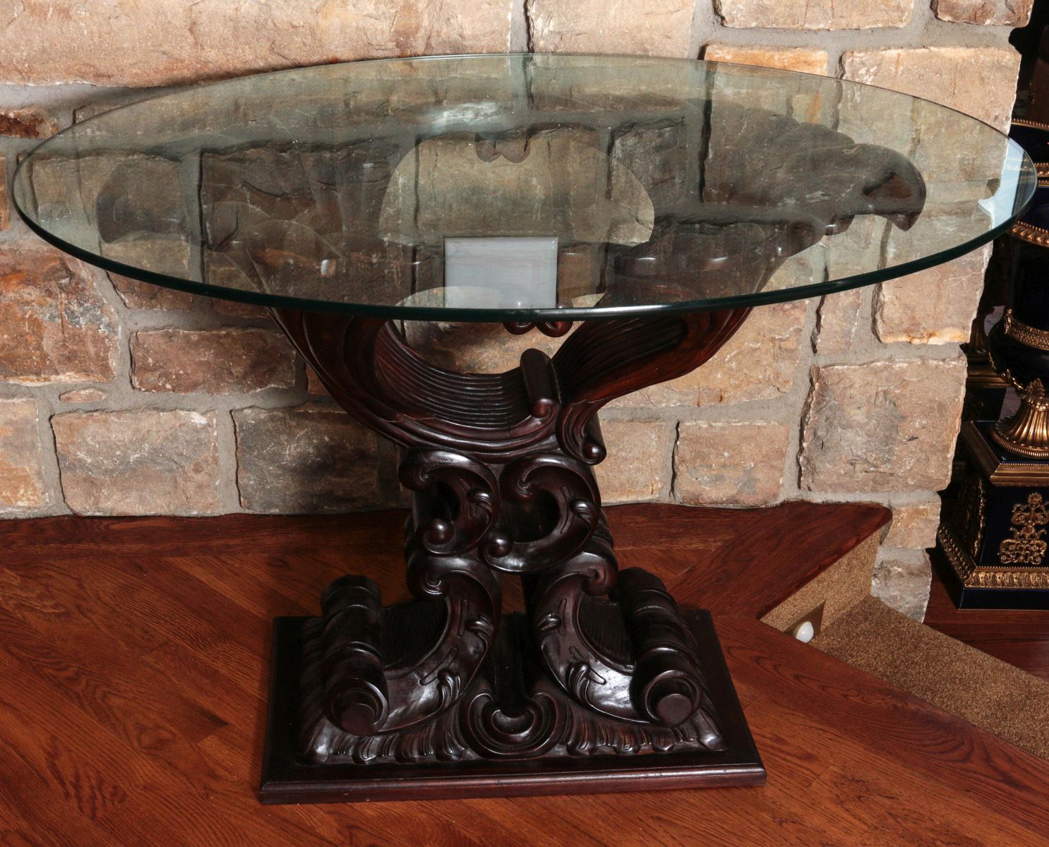 A GLASS TOP SIDE TABLE WITH HEAVY CARVED WOOD BASE