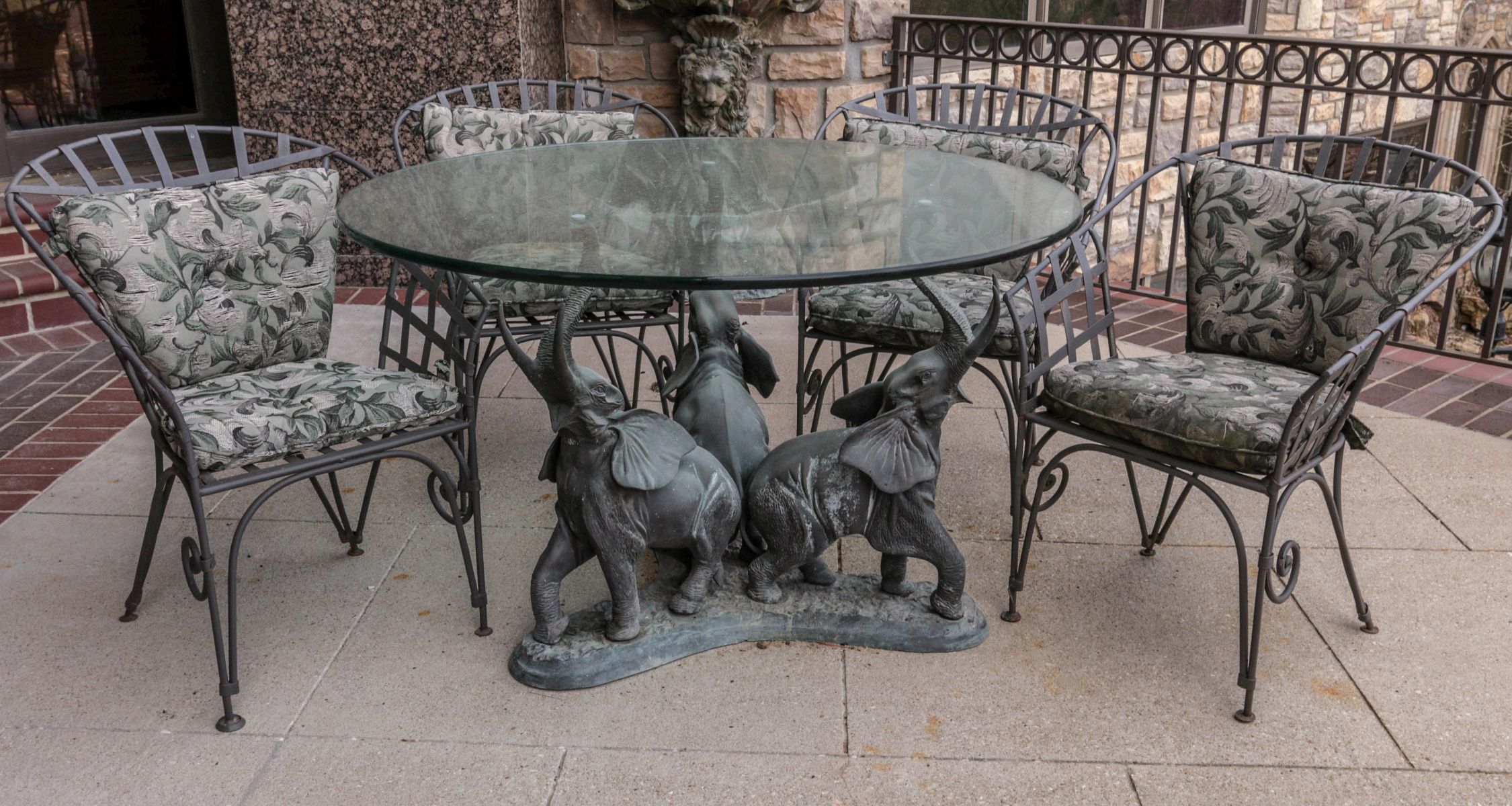 AN OUTDOOR DINING TABLE WITH BRONZE ELEPHANTS BASE