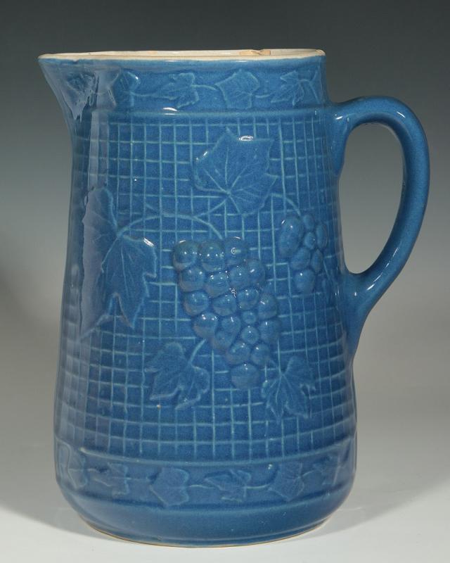 AN ANTIQUE BLUE AND WHITE PITCHER WITH GRAPES