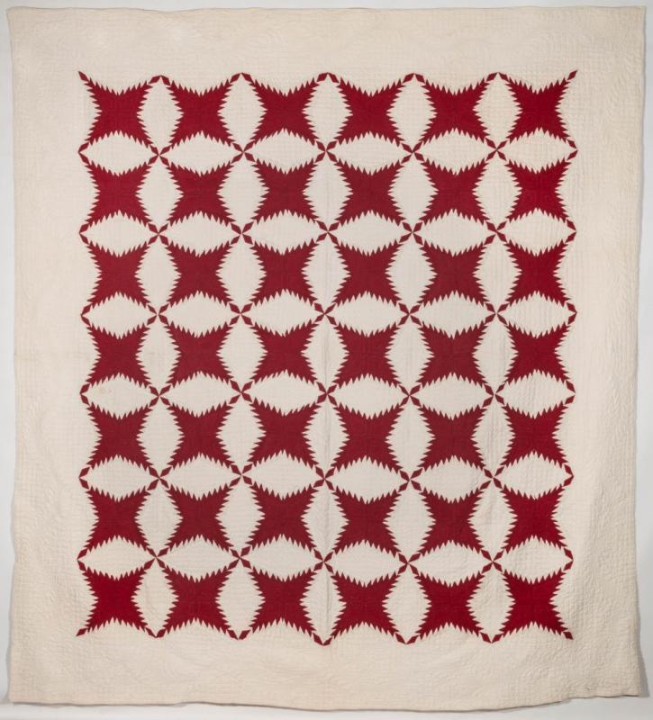 AN ANTIQUE RED AND WHITE PINEAPPLE PATTERN QUILT