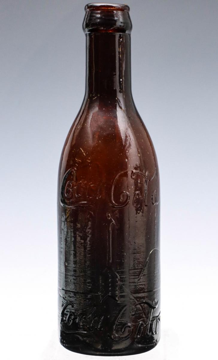 AN AMBER STRAIGHT SIDED COCA COLA BOTTLE CA. 1913