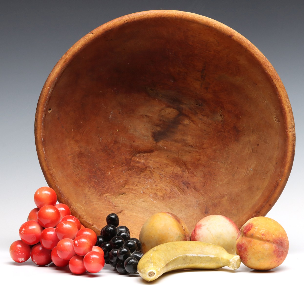 A PRIMITIVE WOOD MIXING BOWL AND STONE FRUIT